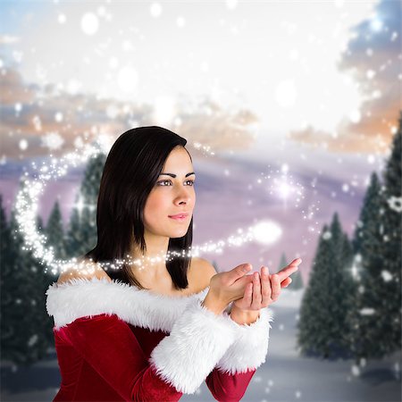 simsearch:400-07755560,k - Pretty girl in santa outfit with hands out against snowy landscape with fir trees Stock Photo - Budget Royalty-Free & Subscription, Code: 400-07755519