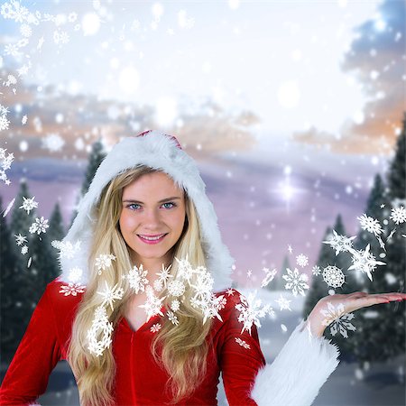 simsearch:400-07755560,k - Pretty girl presenting in santa outfit against snowy landscape with fir trees Stock Photo - Budget Royalty-Free & Subscription, Code: 400-07755529