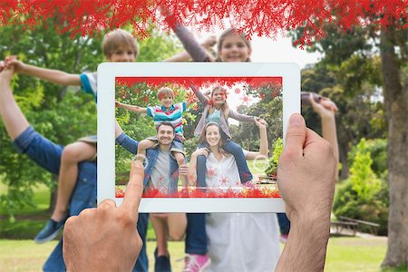 family with tablet in the park - Hand holding tablet pc against parents carrying kids on shoulders at park Photographie de stock - Aubaine LD & Abonnement, Code: 400-07755625