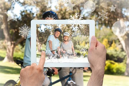 simsearch:400-07664794,k - Hands holding tablet pc against elderly couple with their bikes Stock Photo - Budget Royalty-Free & Subscription, Code: 400-07755647