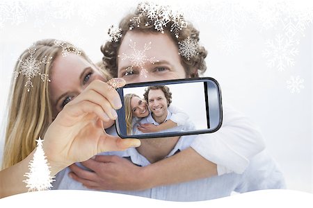 simsearch:400-07664794,k - Hand holding smartphone showing man piggybacking woman at beach Stock Photo - Budget Royalty-Free & Subscription, Code: 400-07755665