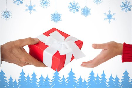 simsearch:400-07726694,k - Couple passing a wrapped gift against snowflakes and fir trees in blue Foto de stock - Royalty-Free Super Valor e Assinatura, Número: 400-07755826