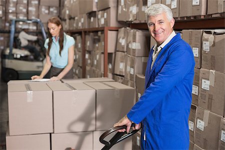 simsearch:400-07750413,k - Warehouse foreman smiling at camera with trolley in a large warehouse Photographie de stock - Aubaine LD & Abonnement, Code: 400-07750363