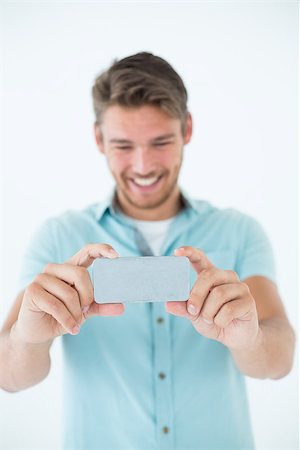 Happy young man looking at his mobile phone over white background Stock Photo - Budget Royalty-Free & Subscription, Code: 400-07750478