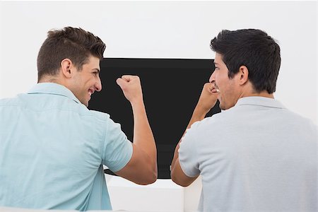 sports fan watching a game on tv - Rear view of two excited soccer fans watching tv Stock Photo - Budget Royalty-Free & Subscription, Code: 400-07750627