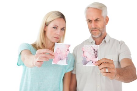 simsearch:400-07685942,k - Mature couple holding two halves of torn photograph over white background Photographie de stock - Aubaine LD & Abonnement, Code: 400-07750735