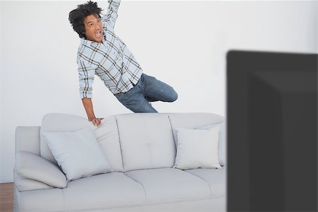 sports fan watching a game on tv - Portrait of a happy soccer fan cheering while watching tv Stock Photo - Budget Royalty-Free & Subscription, Code: 400-07750809