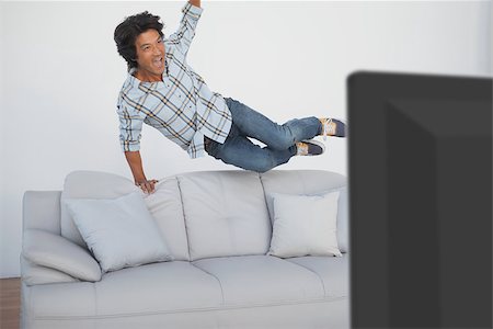 sports fan watching a game on tv - Portrait of a happy soccer fan cheering while watching tv Stock Photo - Budget Royalty-Free & Subscription, Code: 400-07750810