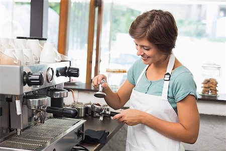 sfregare - Pretty barista pressing coffee grinds at the coffee shop Fotografie stock - Microstock e Abbonamento, Codice: 400-07750873
