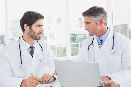 simsearch:640-03257612,k - Doctor sitting and taking notes with fellow doctor on a laptop Stock Photo - Budget Royalty-Free & Subscription, Code: 400-07752055