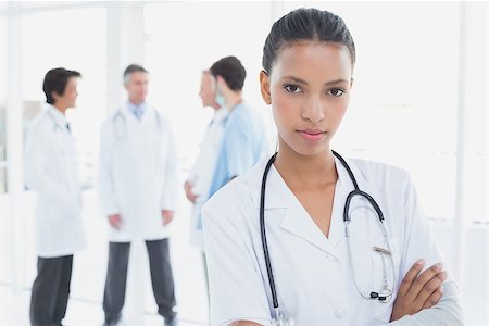 simsearch:400-06799497,k - Serious doctor looking at camera with colleagues behind her Stockbilder - Microstock & Abonnement, Bildnummer: 400-07752085