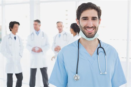 simsearch:400-06799497,k - Smiling doctor looking at camera with co-workers behind him Stockbilder - Microstock & Abonnement, Bildnummer: 400-07752086