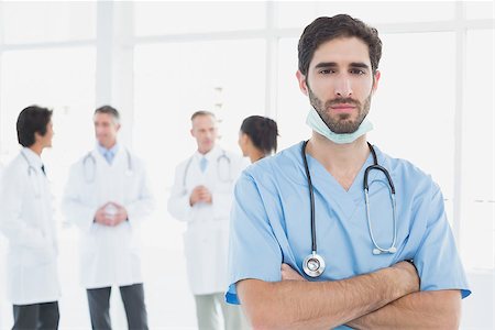 simsearch:400-06799497,k - Serious doctor looking at camera with colleagues behind him Stockbilder - Microstock & Abonnement, Bildnummer: 400-07752087