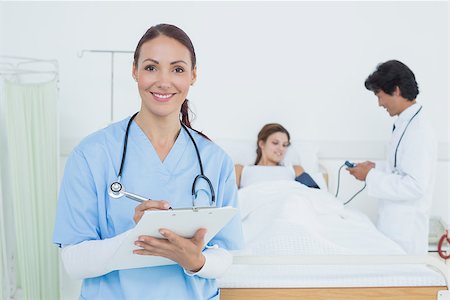 simsearch:685-02938526,k - Nurse looking at the camera with doctor in the background Stock Photo - Budget Royalty-Free & Subscription, Code: 400-07752105