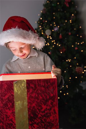 simsearch:400-07753751,k - Child opening his christmas present with tree behind him Stock Photo - Budget Royalty-Free & Subscription, Code: 400-07753754