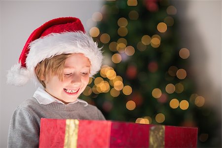 Child opening his christmas present with tree behind him Stock Photo - Budget Royalty-Free & Subscription, Code: 400-07753757