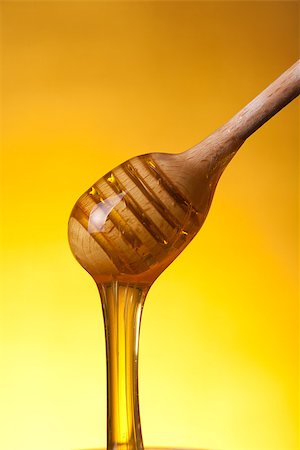 simsearch:400-06640106,k - Close-up shot of wooden drizzler with flowing honey over yellow background Stock Photo - Budget Royalty-Free & Subscription, Code: 400-07776245
