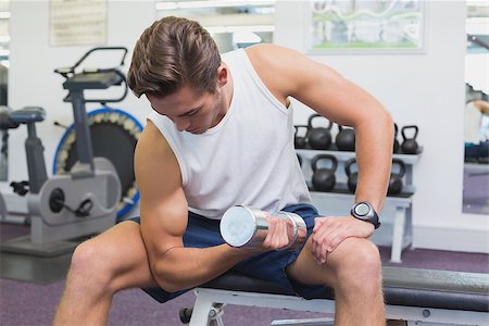 simsearch:400-07333355,k - Fit man lifting dumbbells sitting on the bench at the gym Stock Photo - Budget Royalty-Free & Subscription, Code: 400-07777657