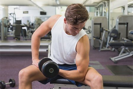 simsearch:400-07333355,k - Fit man lifting dumbbells sitting on the bench at the gym Stock Photo - Budget Royalty-Free & Subscription, Code: 400-07777660