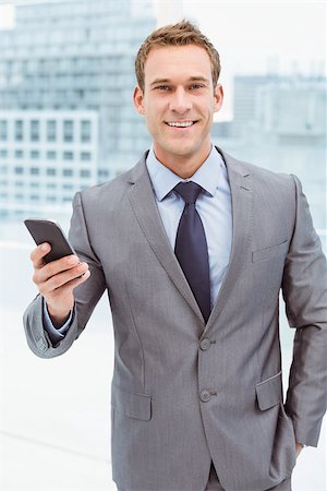 simsearch:400-07927298,k - Portrait of smart young businessman holding mobile phone in office Foto de stock - Royalty-Free Super Valor e Assinatura, Número: 400-07777755
