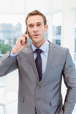 simsearch:400-07927298,k - Smart young businessman using mobile phone in office Foto de stock - Royalty-Free Super Valor e Assinatura, Número: 400-07777751