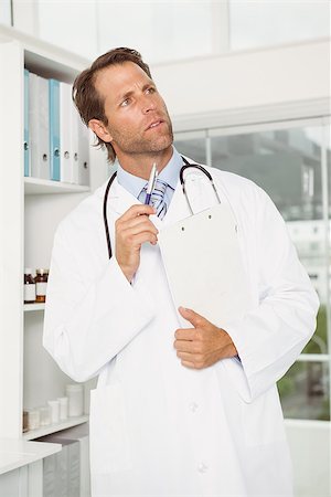 simsearch:400-07334526,k - Thoughtful male doctor with reports looking away at the medical office Stock Photo - Budget Royalty-Free & Subscription, Code: 400-07778508