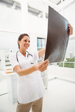 simsearch:400-07274751,k - Smiling female doctor examining x-ray in the medical office Foto de stock - Super Valor sin royalties y Suscripción, Código: 400-07778539