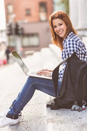 simsearch:400-07778671,k - Portrait of a woman using her laptop and smiling at camera in the street Fotografie stock - Microstock e Abbonamento, Codice: 400-07778589