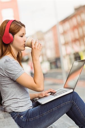 Girl using laptop, listening music and drinking coffee in the street Stock Photo - Budget Royalty-Free & Subscription, Code: 400-07778591