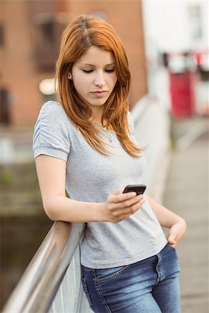 simsearch:400-07778671,k - Cheerful redhead with her mobile phone texting a message in the city Fotografie stock - Microstock e Abbonamento, Codice: 400-07778642