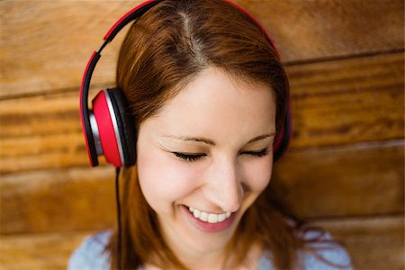 simsearch:400-07778671,k - Natural smiling redhead listening to music with closed eyes in the city Fotografie stock - Microstock e Abbonamento, Codice: 400-07778655