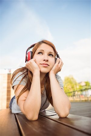 simsearch:400-07778671,k - Pretty redhead lying on bench listening to music in the city Fotografie stock - Microstock e Abbonamento, Codice: 400-07778664