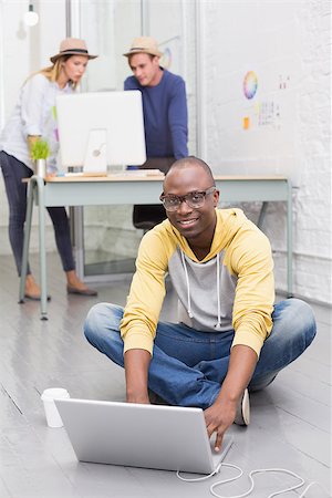 Young casual man using laptop with colleagues behind in the office Stock Photo - Budget Royalty-Free & Subscription, Code: 400-07778848