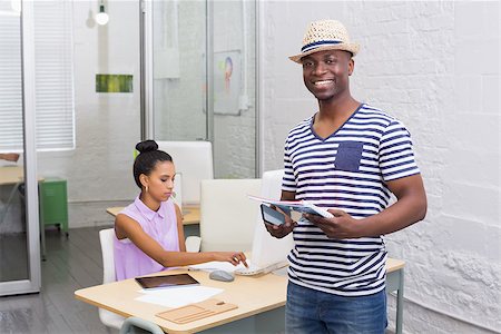 Portrait of young casual man with colleague using computer behind in the office Stock Photo - Budget Royalty-Free & Subscription, Code: 400-07778877