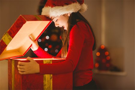 simsearch:400-07753751,k - Festive little girl opening a glowing christmas gift at home in the living room Stock Photo - Budget Royalty-Free & Subscription, Code: 400-07779109