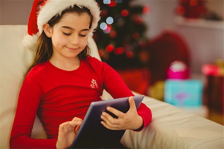 Festive little girl using tablet pc on couch at home in the living room Stock Photo - Budget Royalty-Free & Subscription, Code: 400-07779114