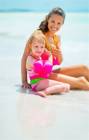 Portrait of mother and baby girl listening sound of sea in shell at seaside Stock Photo - Budget Royalty-Free & Subscription, Code: 400-07772383