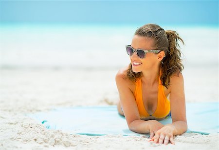 simsearch:400-06639191,k - Smiling young woman in sunglasses laying on sea coast looking on copy space Stock Photo - Budget Royalty-Free & Subscription, Code: 400-07772395