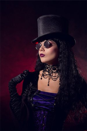 simsearch:400-07209173,k - Vampire gothic girl in tophat and round eyeglasses, studio shot with smoke background Fotografie stock - Microstock e Abbonamento, Codice: 400-07772556