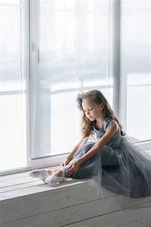 simsearch:400-05924060,k - Little ballerina in gray dress puts on ballet shoes pointe front of the window. Foto de stock - Super Valor sin royalties y Suscripción, Código: 400-07772673