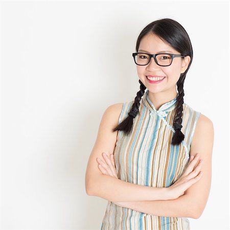 Portrait of beautiful Asian Chinese female smiling and looking at camera, in old-fashioned style cheongsam, standing on plain background. Stock Photo - Budget Royalty-Free & Subscription, Code: 400-07772742