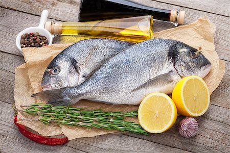 Fresh dorado fish cooking with spices and condiments on wooden table Stockbilder - Microstock & Abonnement, Bildnummer: 400-07773209