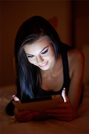 simsearch:400-05364625,k - Beautiful woman reading an e-book at night as the glow from the screen of her tablet computer illuminates her face in the darkness Foto de stock - Super Valor sin royalties y Suscripción, Código: 400-07773653