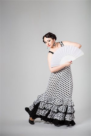 dances of andalucia - young beautiful brunette female spanish flamenco dancer in black and white flamenco dress dancing with white fan in studio on gray background Stock Photo - Budget Royalty-Free & Subscription, Code: 400-07795286