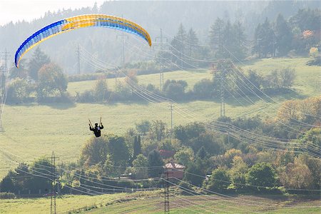 Paraglider flying dangerously low over high voltage pylons and wiring before he lands. Stockbilder - Microstock & Abonnement, Bildnummer: 400-07796922
