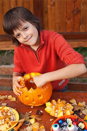 simsearch:400-07793717,k - Boy preparing for Halloween - carving a pumpkin jack-o-lantern outdoors Photographie de stock - Aubaine LD & Abonnement, Code: 400-07793715