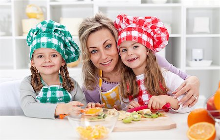 Happy chefs in the kitchen - woman and little girls portrait preparing fruit salad Photographie de stock - Aubaine LD & Abonnement, Code: 400-07793733