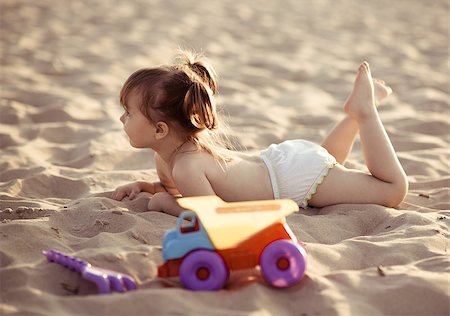Adorable baby girl lying in the sand on the beach Stock Photo - Budget Royalty-Free & Subscription, Code: 400-07793862