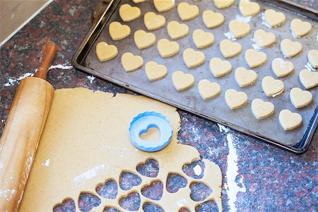 Heart shaped cookies in the making next to a wooden rolling pin, raw dough and heart shaped cookie cutter Stock Photo - Budget Royalty-Free & Subscription, Code: 400-07817324