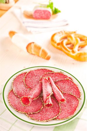 simsearch:400-06852716,k - Delicious salami slices on plate with pastry, salami piece and fresh herbs in background. Culinary meat concept. Stockbilder - Microstock & Abonnement, Bildnummer: 400-07817723